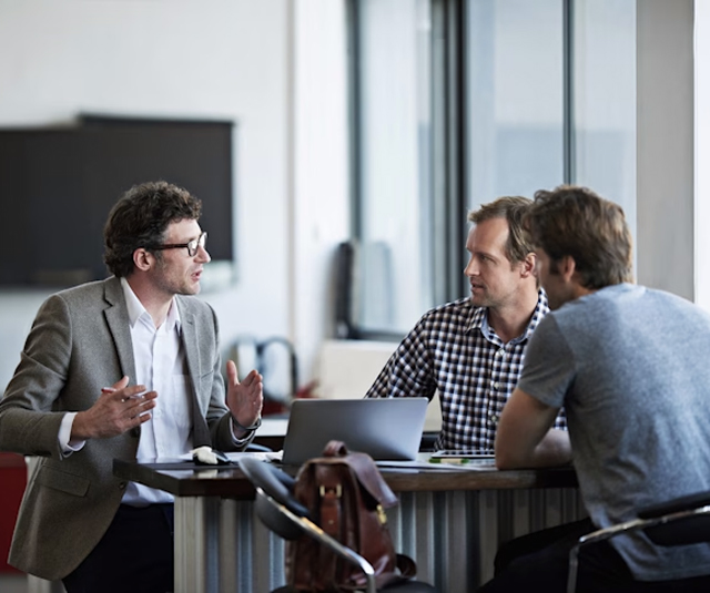 An adviser discussing preparation documents with two people at a meeting